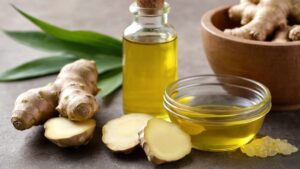 Raiz de gengibre fresca ao lado de um pequeno recipiente com óleo infundido